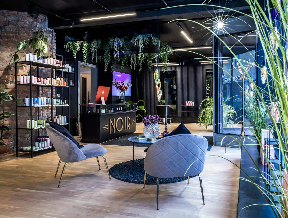 Salongens reception och lounge med gröna växter, skylt med NOIR och modern inredning.