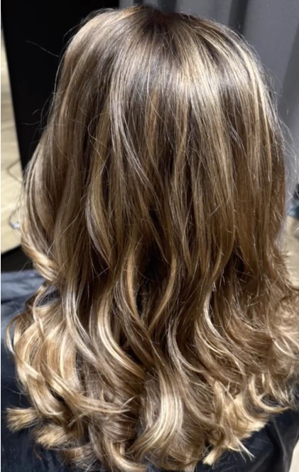 Axellångt, vågigt hår med ljusa slingor och mörkare rötter, sett bakifrån